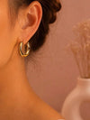 Gewellte Ohrringe aus goldfarbenem Edelstahl – Skulpturales Design und moderner Glanz.