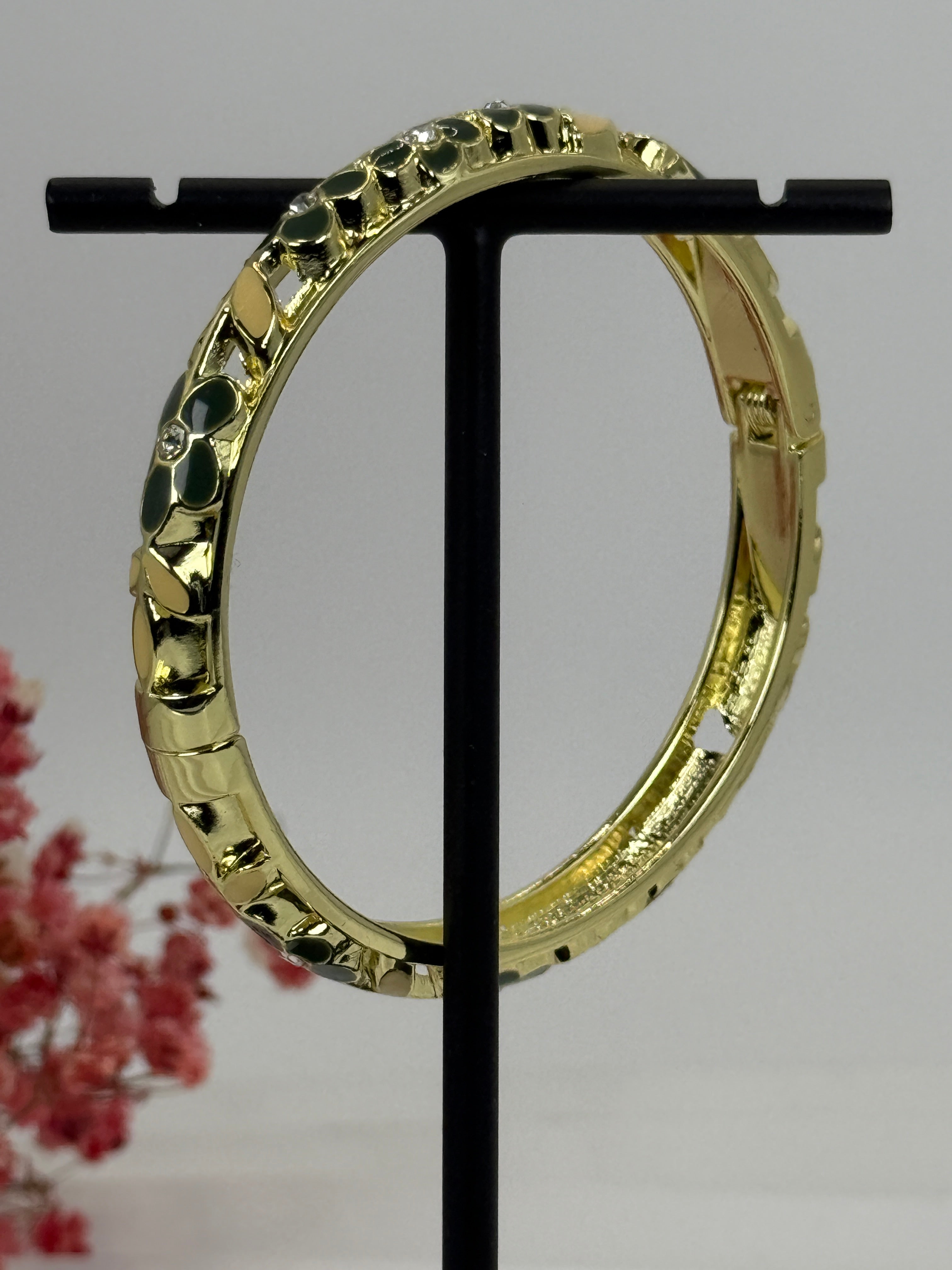 Scharnierende messing vergulde armband met groen en geel geëmailleerd bloemmotief – binnendiameter 6 cm.