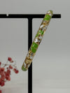Bracelet jonc ouvrable en laiton doré motif floral émaillé vert et blanc – diamètre intérieur 6 cm.