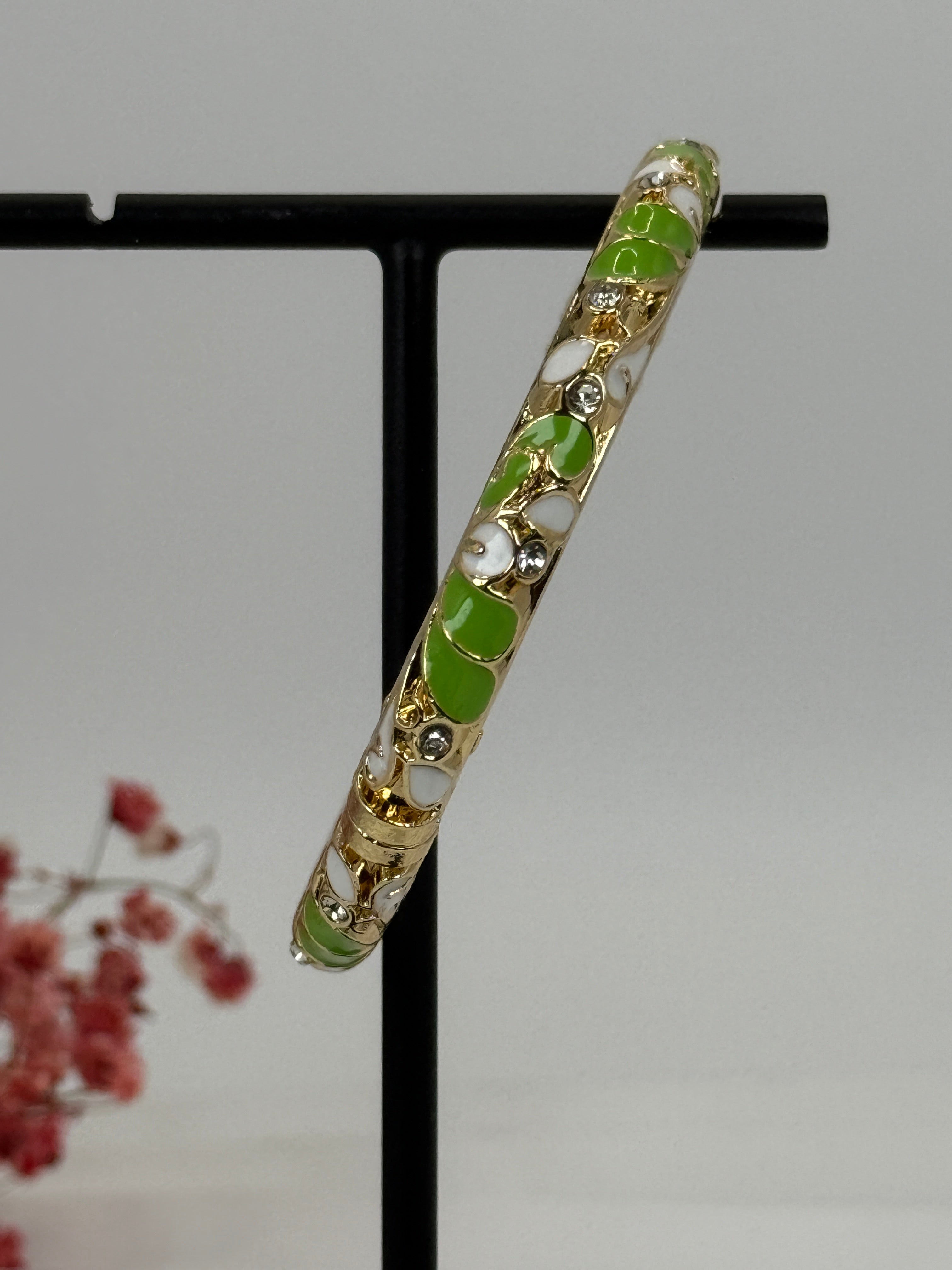Opvouwbare messing vergulde armband met geëmailleerd groen en wit bloemmotief – binnendiameter 6 cm.