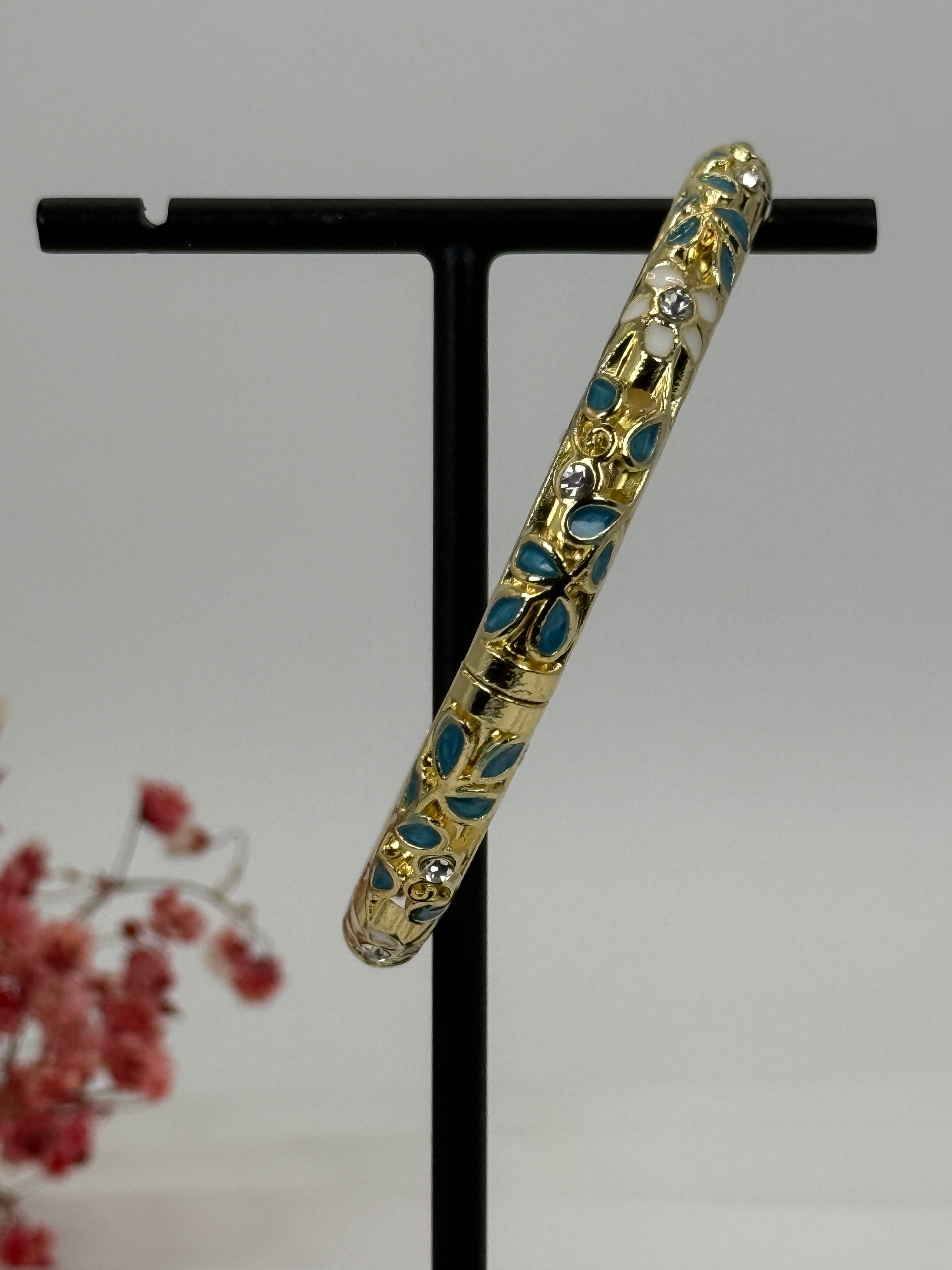 Open bRASSLET met vergulde, blauw (1) en wit geëmailleerd bloemmotief – binnendiameter 6 cm.
