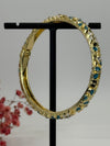 Armreif, aufklappbar, aus vergoldetem Messing, emailliertes Blumenmotiv in Blau (1) und Weiß – Innendurchmesser 6 cm.