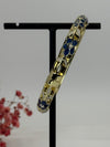 Aufklappbarer Armreif aus vergoldetem Messing mit floralem Muster in blauem (3) und weißem Emaille – Innendurchmesser 6 cm.