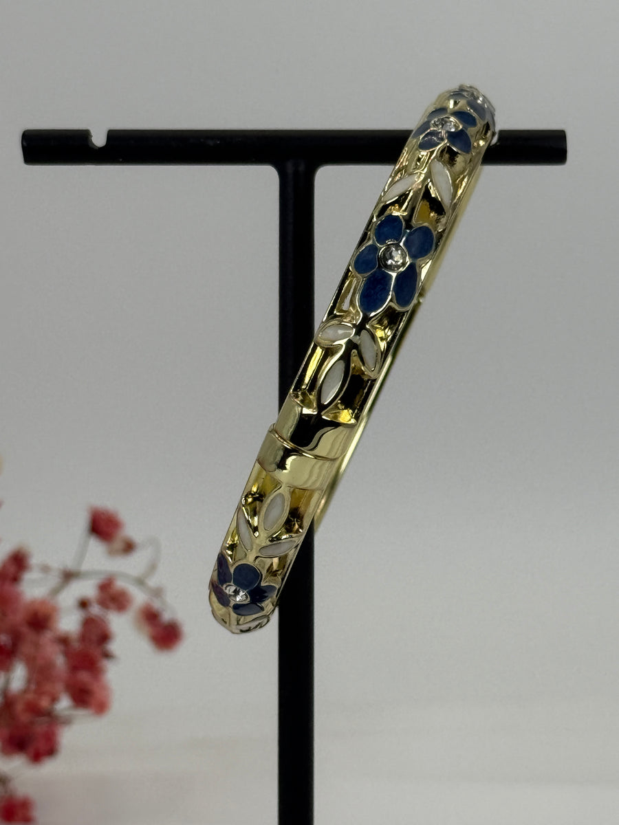 Aufklappbarer Armreif aus vergoldetem Messing mit floralem Muster in blauem (3) und weißem Emaille – Innendurchmesser 6 cm.