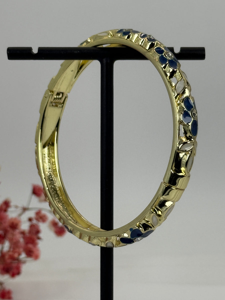 Aufklappbarer Armreif aus vergoldetem Messing mit floralem Muster in blauem (3) und weißem Emaille – Innendurchmesser 6 cm.