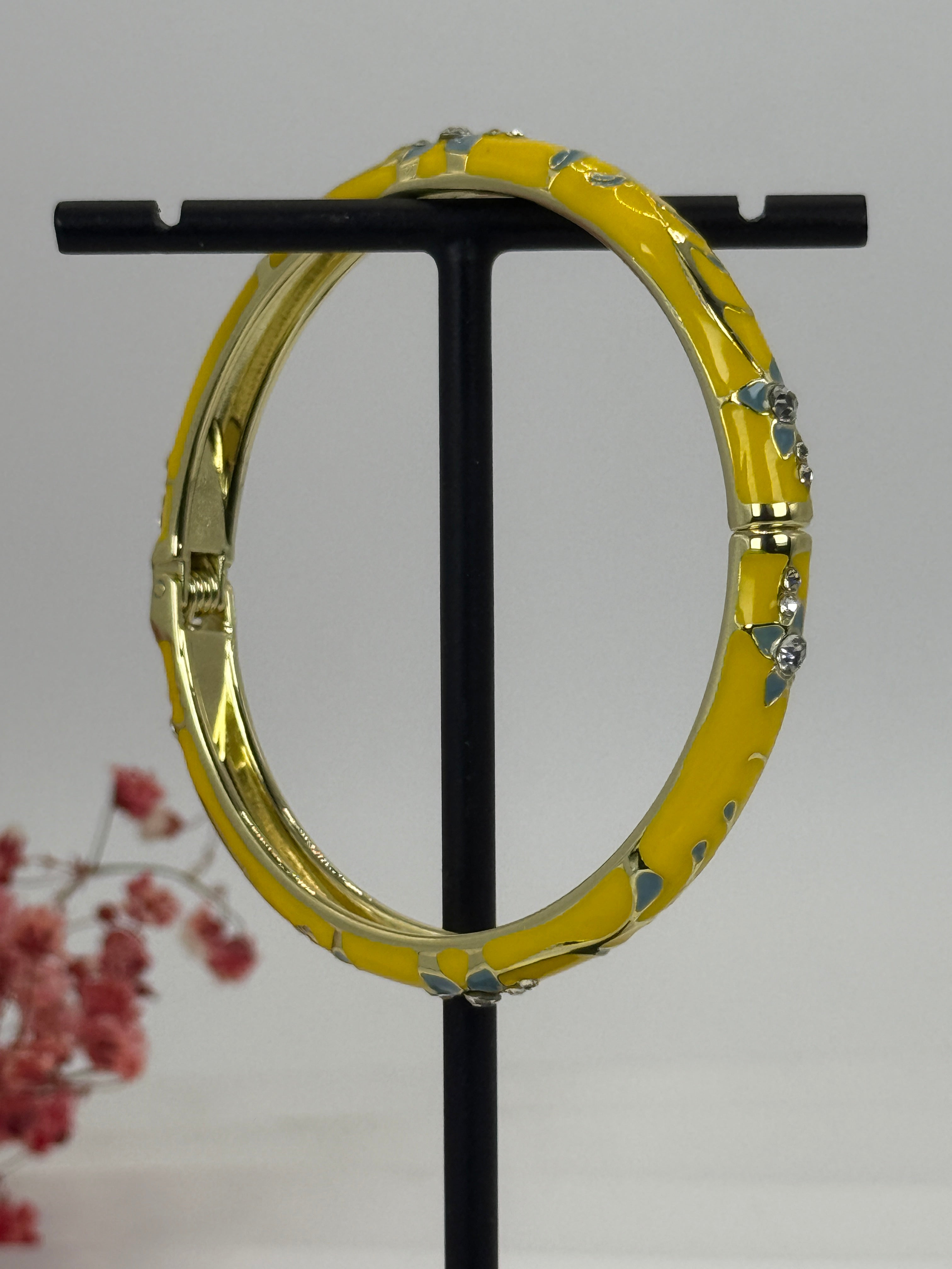 Goudkleurige opvouwbare messing armband met geëmailleerd geel bloemmotief - binnendiameter 6 cm