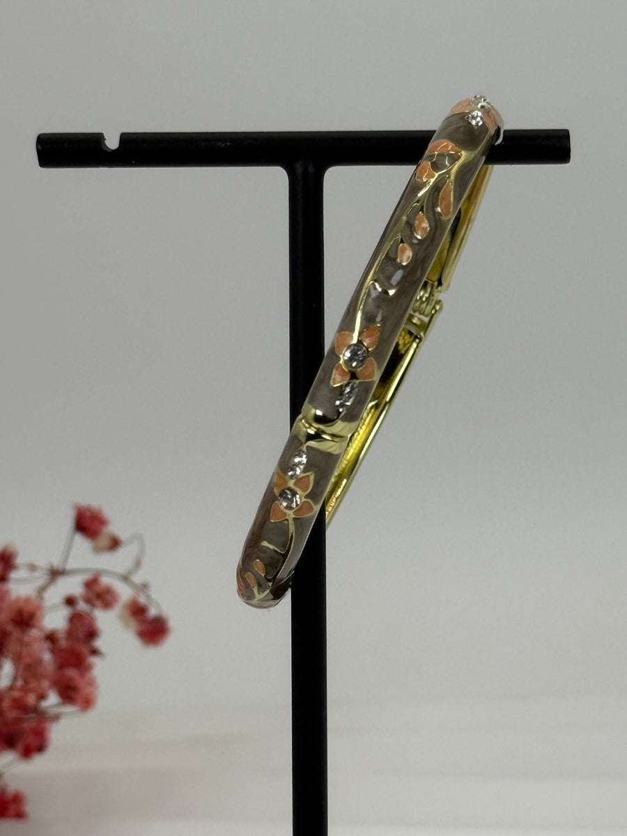 Öffnbarer Armreif aus vergoldetem Messing mit floralem Muster in Grau/Taupe emailliert – Innendurchmesser 6 cm.