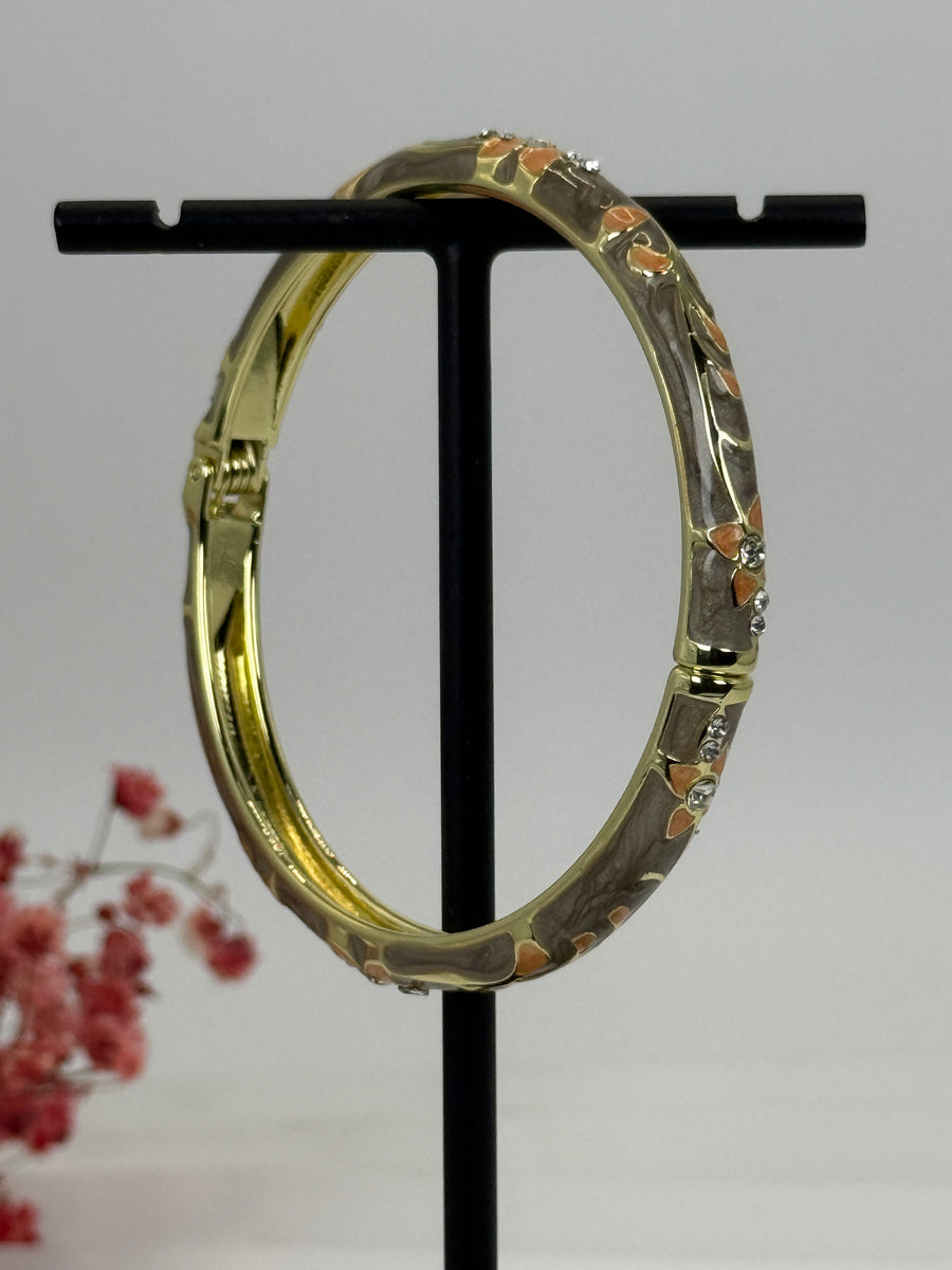 Öffnbarer Armreif aus vergoldetem Messing mit floralem Muster in Grau/Taupe emailliert – Innendurchmesser 6 cm.